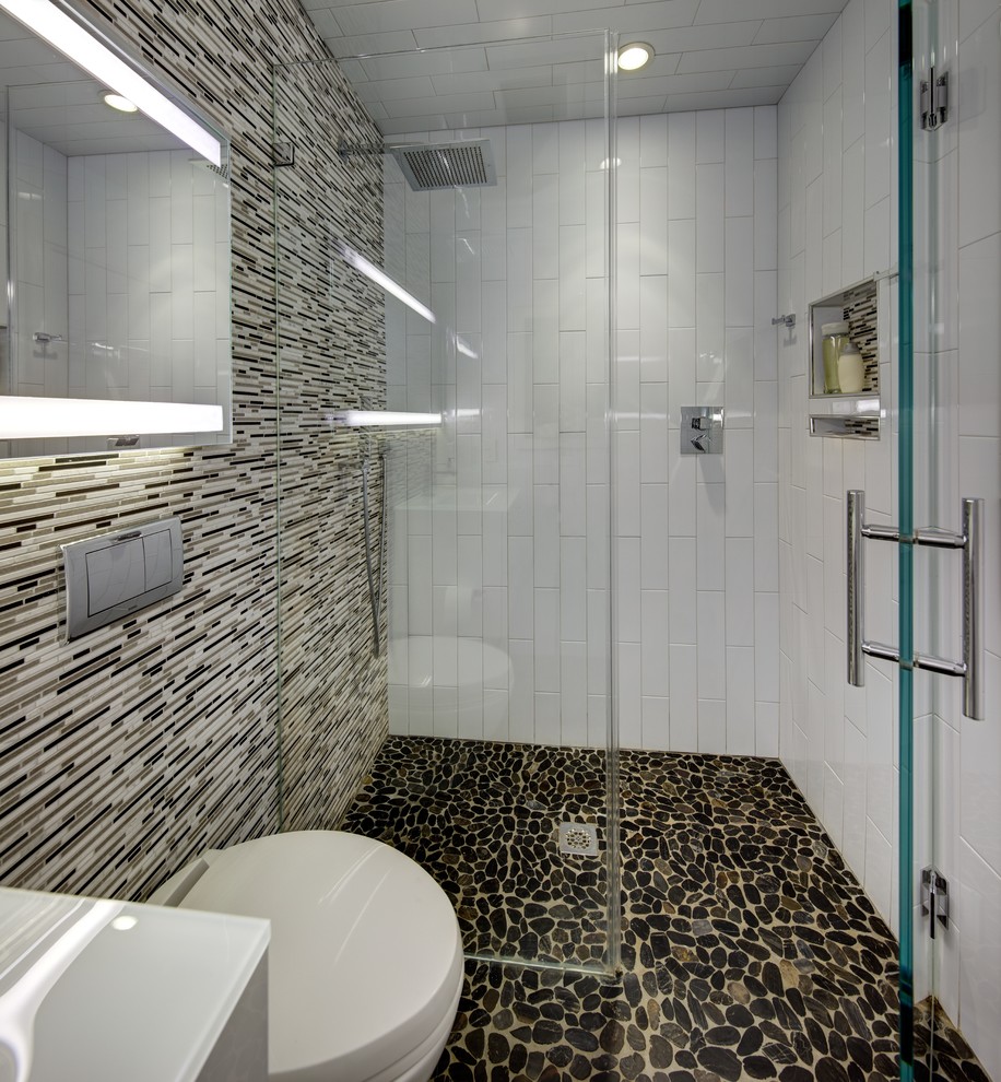 Small modern master bathroom in New York with flat-panel cabinets, white cabinets, a curbless shower, a wall-mount toilet, black and white tile, matchstick tile, white walls, pebble tile floors, glass benchtops and an integrated sink.