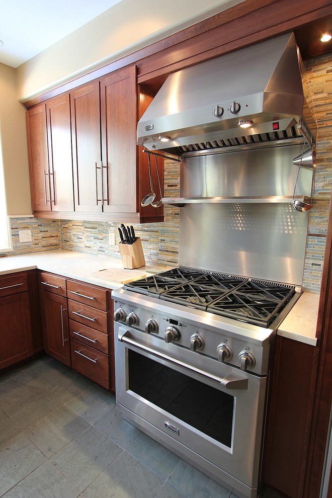 Example of a large transitional l-shaped slate floor kitchen design with an undermount sink, recessed-panel cabinets, medium tone wood cabinets, granite countertops, multicolored backsplash, matchstick tile backsplash, stainless steel appliances and an island