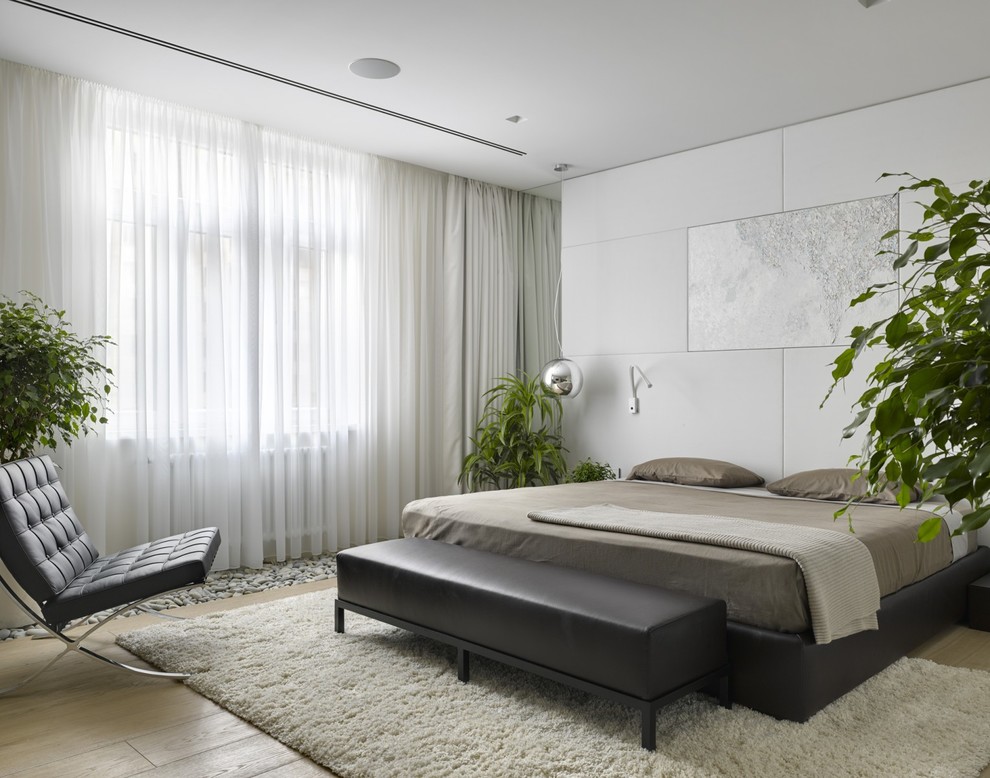 Свежая идея для дизайна: хозяйская спальня среднего размера с белыми стенами, светлым паркетным полом, двусторонним камином и фасадом камина из камня - отличное фото интерьера