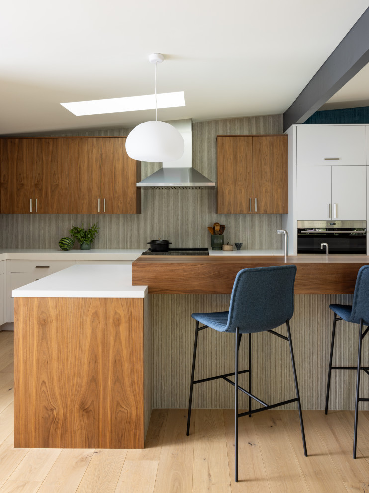 This is an example of a medium sized midcentury l-shaped kitchen/diner in Sacramento with a submerged sink, flat-panel cabinets, beige cabinets, engineered stone countertops, grey splashback, ceramic splashback, stainless steel appliances, ceramic flooring, an island, beige floors, white worktops and exposed beams.