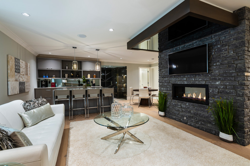 Example of a mid-sized transitional underground light wood floor and beige floor basement design in Vancouver with gray walls, a two-sided fireplace and a stone fireplace