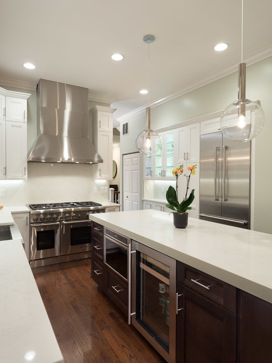 Inspiration for a large transitional l-shaped dark wood floor eat-in kitchen remodel in Chicago with a farmhouse sink, shaker cabinets, white cabinets, marble countertops, white backsplash, subway tile backsplash, stainless steel appliances and an island
