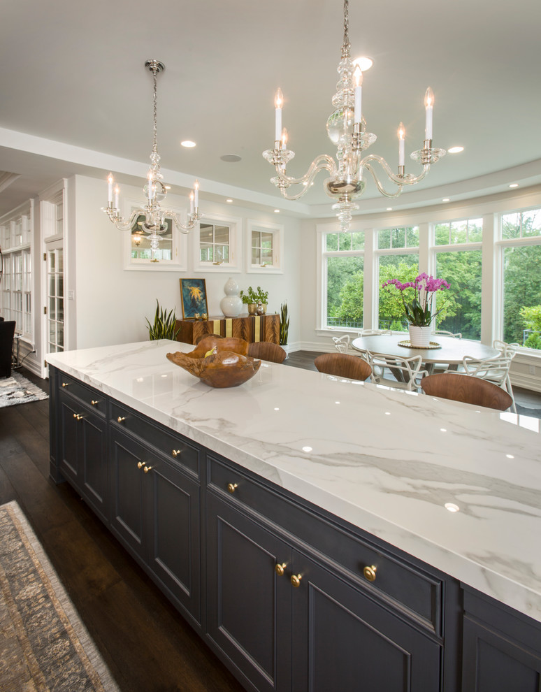 Inspiration for a large traditional l-shaped kitchen in Cincinnati with a farmhouse sink, glass-front cabinets, white cabinets, quartz benchtops, white splashback, stone slab splashback, panelled appliances, dark hardwood floors and multiple islands.