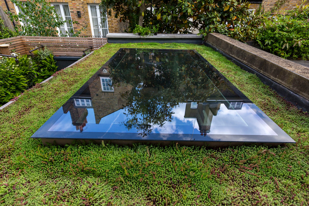 Small contemporary backyard partial sun garden in London with a vertical garden and natural stone pavers for summer.