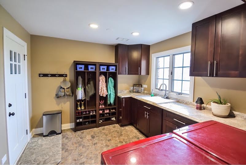 Inspiration for a large traditional u-shaped utility room in Chicago with an utility sink, shaker cabinets, dark wood cabinets, granite benchtops, brown walls, porcelain floors, a side-by-side washer and dryer and beige floor.