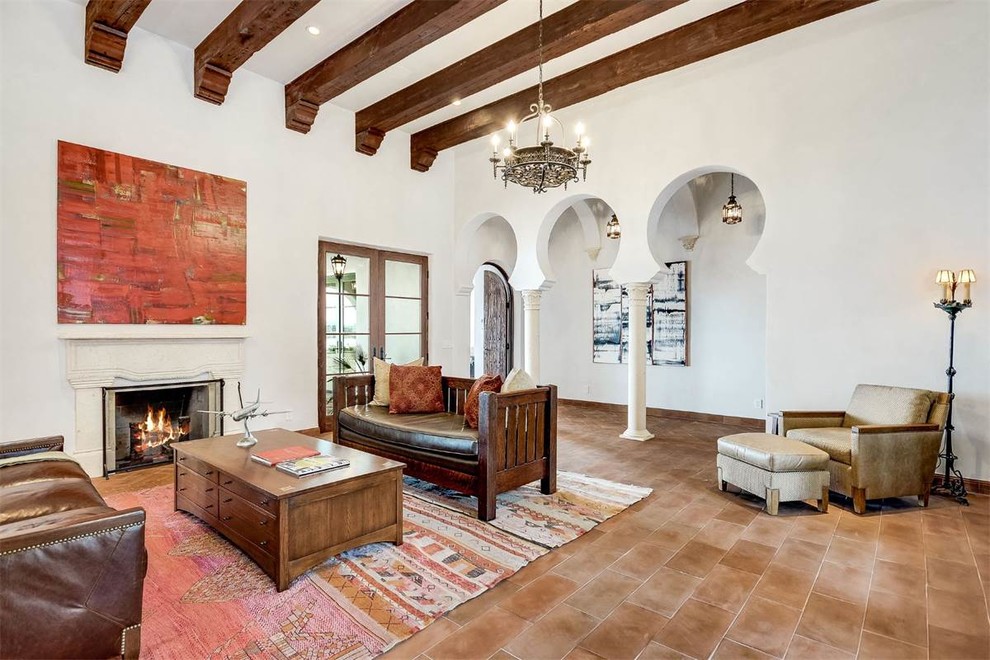 Large mediterranean open concept living room in Austin with white walls, terra-cotta floors, a standard fireplace and red floor.