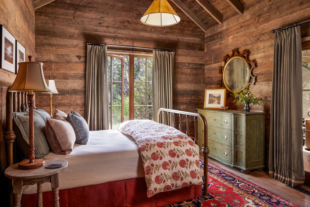 Example of a mountain style medium tone wood floor bedroom design in Other with brown walls and no fireplace