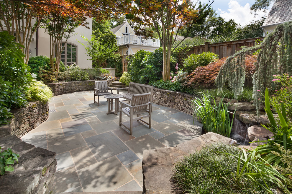 This is an example of a traditional patio in DC Metro with natural stone pavers, no cover and a water feature.