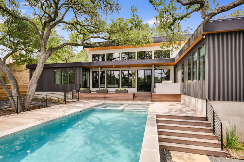 Design ideas for a mid-sized midcentury backyard rectangular natural pool in Austin with a hot tub and decking.