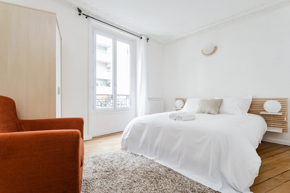 Midcentury master bedroom in Paris with medium hardwood floors, beige floor and recessed.