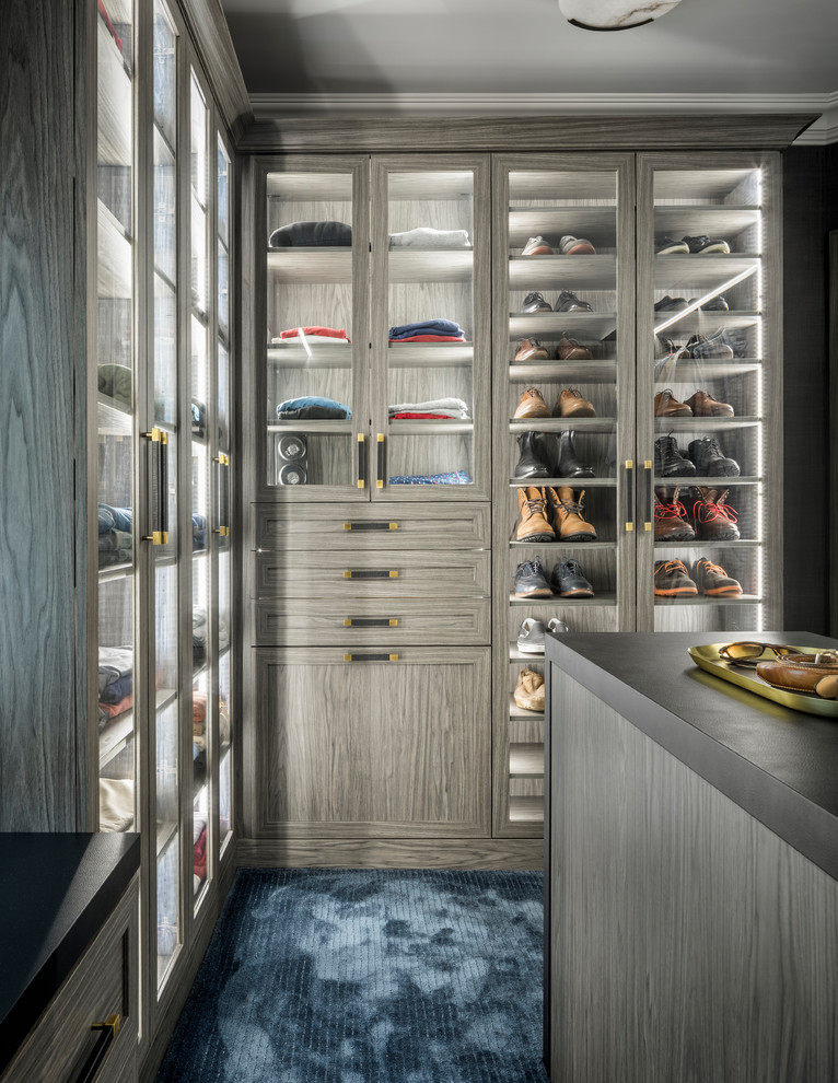 Photo of a transitional men's walk-in wardrobe in New York with glass-front cabinets, carpet and blue floor.