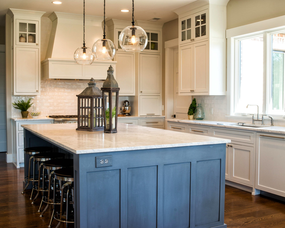 Large transitional l-shaped medium tone wood floor open concept kitchen photo with an undermount sink, flat-panel cabinets, white cabinets, marble countertops, white backsplash, ceramic backsplash, stainless steel appliances and an island