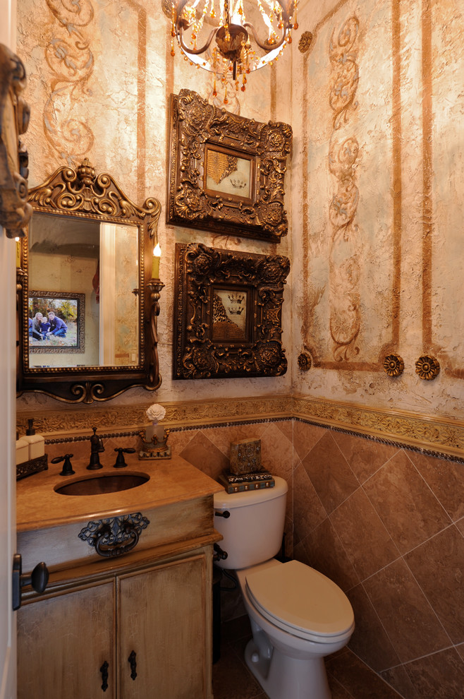 Mid-sized traditional powder room in Dallas with flat-panel cabinets, distressed cabinets, a two-piece toilet, brown tile, ceramic tile, brown walls and an undermount sink.