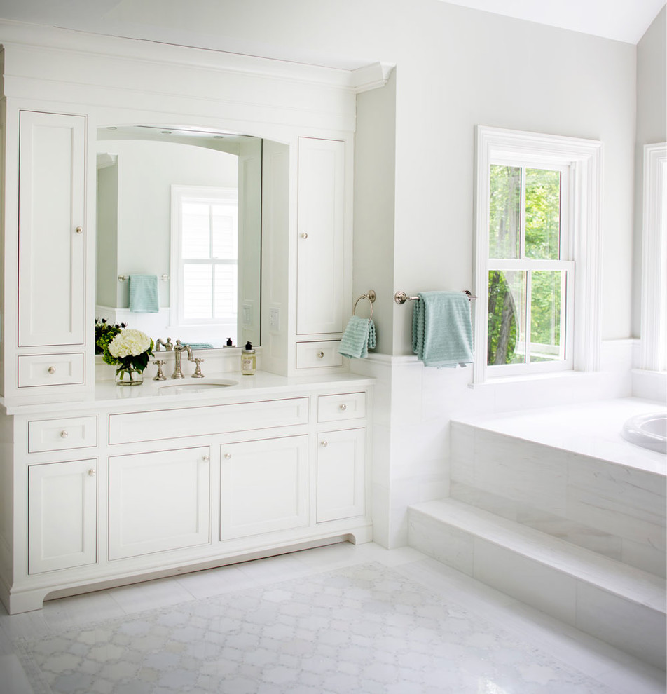 This is an example of a large beach style master bathroom in New York with recessed-panel cabinets, white cabinets, a drop-in tub, white tile, stone tile, green walls, marble floors and marble benchtops.