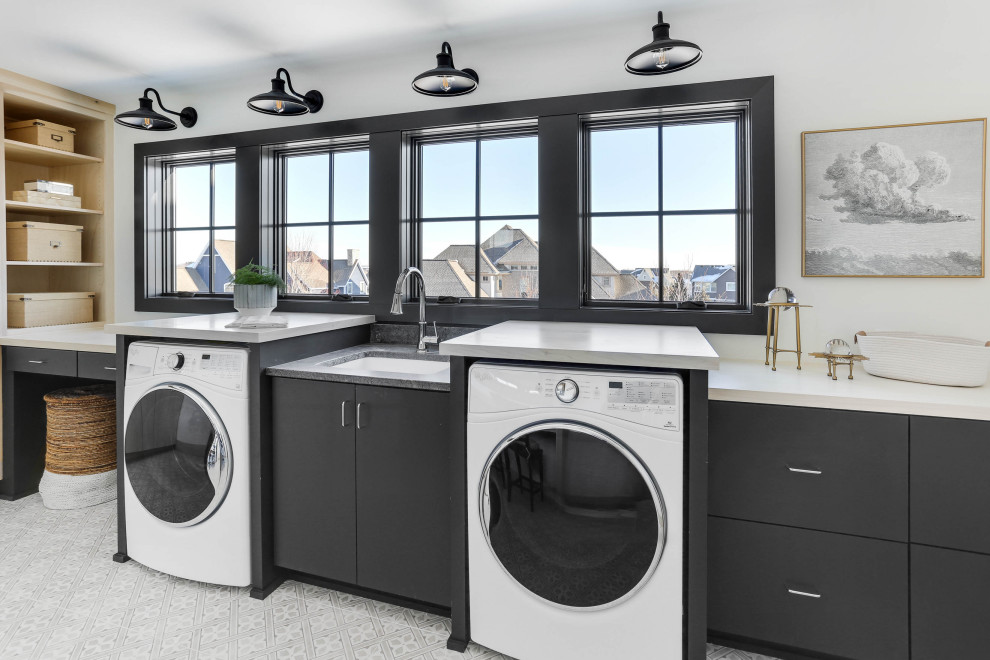 Transitional single-wall laundry room in Minneapolis with an undermount sink, flat-panel cabinets, black cabinets, white walls, a side-by-side washer and dryer, grey floor and white benchtop.