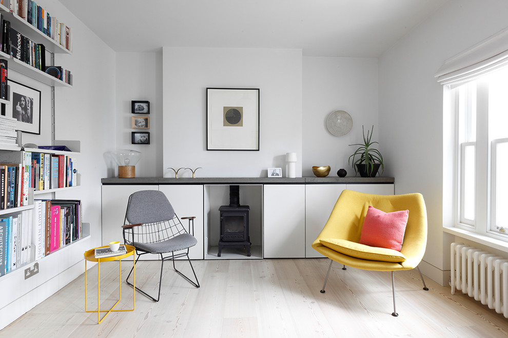 This is an example of a mid-sized scandinavian enclosed living room in London with a library, white walls, no tv, medium hardwood floors and beige floor.