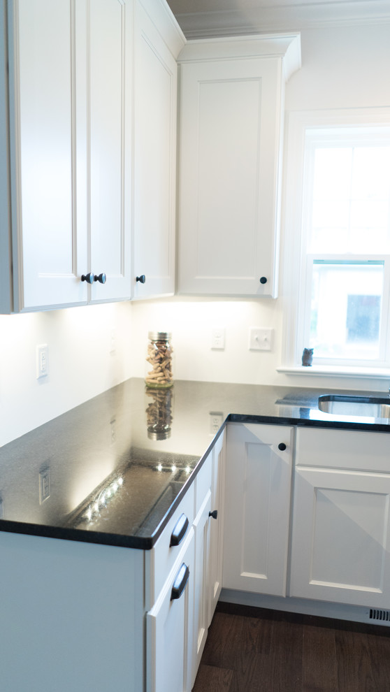 Open concept kitchen - mid-sized transitional l-shaped dark wood floor open concept kitchen idea with an undermount sink, shaker cabinets, white cabinets, granite countertops, gray backsplash, stainless steel appliances and an island