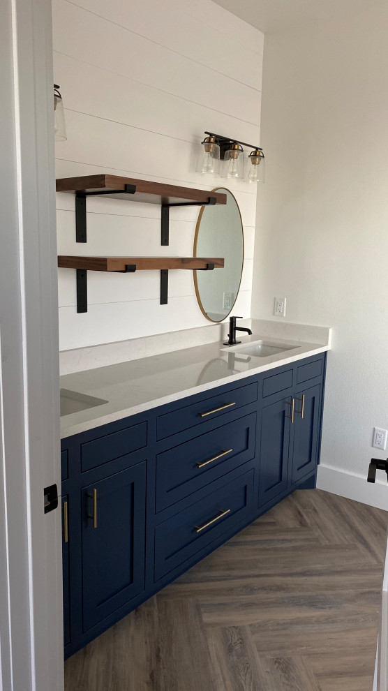 Photo of a mid-sized transitional master bathroom in Other with flat-panel cabinets, blue cabinets, a drop-in tub, a corner shower, a two-piece toilet, white tile, white walls, vinyl floors, an undermount sink, quartzite benchtops, brown floor, a hinged shower door, white benchtops, a double vanity, a built-in vanity and planked wall panelling.
