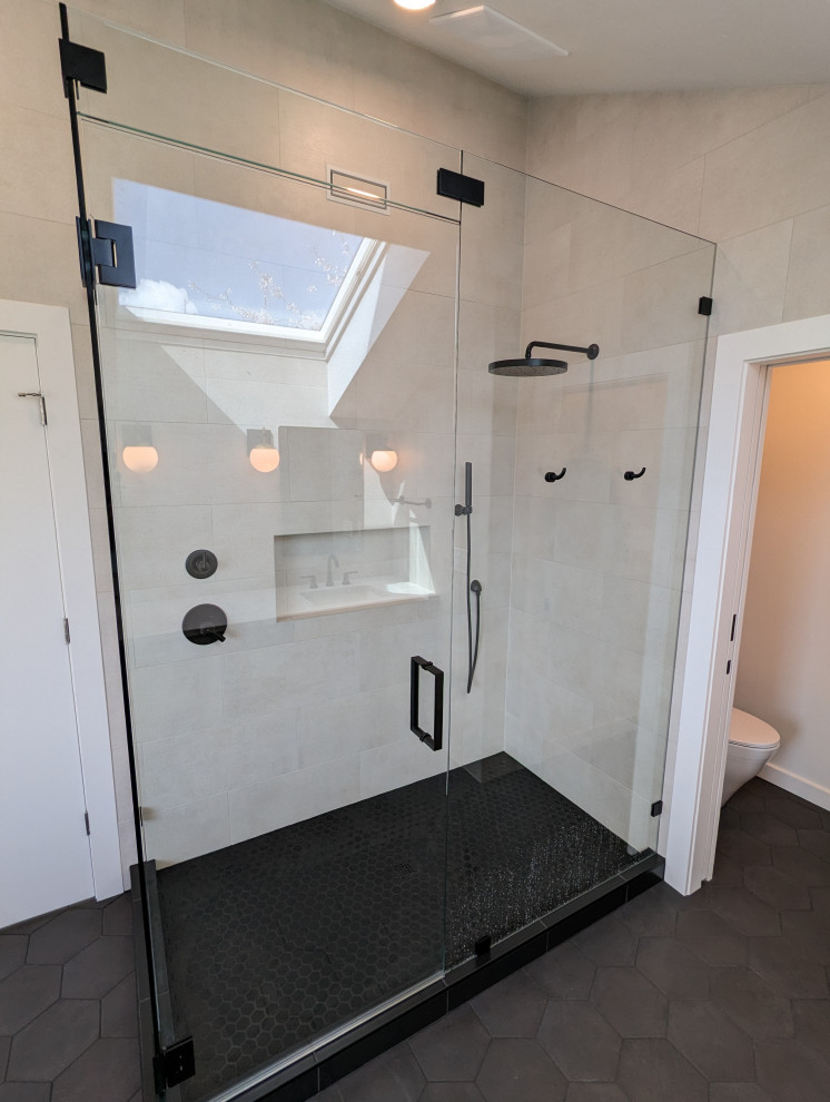 Cette image montre une grande salle de bain principale minimaliste avec un placard à porte plane, une baignoire indépendante, une douche d'angle, un carrelage beige, des carreaux de céramique, un sol en carrelage de porcelaine, un sol noir, une cabine de douche à porte battante, des toilettes cachées, meuble-lavabo suspendu et un plafond voûté.