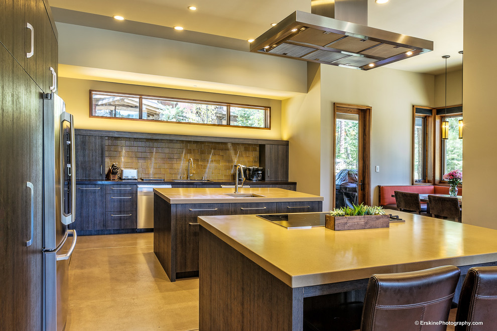 Photo of a large contemporary u-shaped eat-in kitchen in Sacramento with a drop-in sink, flat-panel cabinets, dark wood cabinets, concrete benchtops, beige splashback, metal splashback, stainless steel appliances, concrete floors and multiple islands.