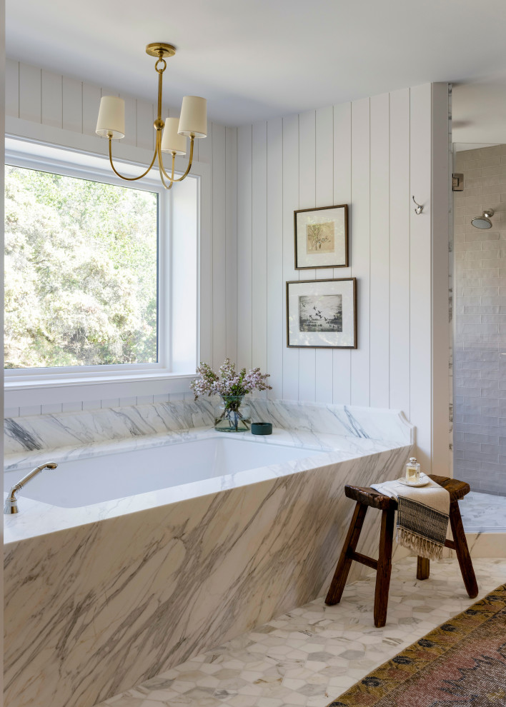 Пример оригинального дизайна: огромная главная ванная комната в стиле кантри с фасадами с выступающей филенкой, синими фасадами, душем в нише, унитазом-моноблоком, белой плиткой, белыми стенами, полом из известняка, накладной раковиной, мраморной столешницей, серым полом, душем с распашными дверями, белой столешницей, сиденьем для душа, тумбой под одну раковину и встроенной тумбой