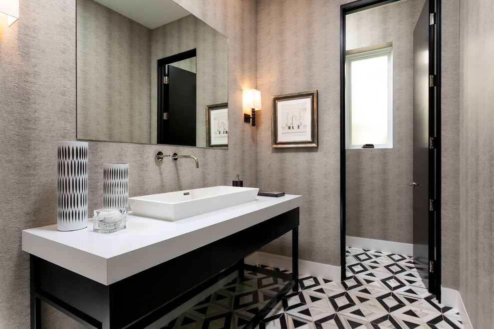 Inspiration for a large contemporary powder room in Orange County with a vessel sink, multi-coloured floor, white benchtops, flat-panel cabinets, black cabinets, grey walls and porcelain floors.