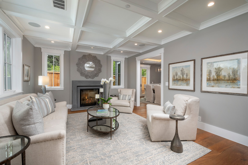 This is an example of a transitional formal enclosed living room in San Francisco with grey walls, a standard fireplace, a concrete fireplace surround and medium hardwood floors.