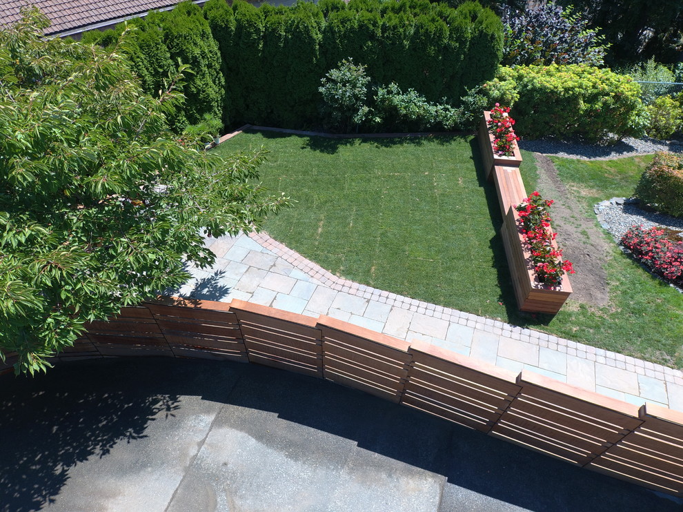 Large modern backyard partial sun garden in Seattle with brick pavers.