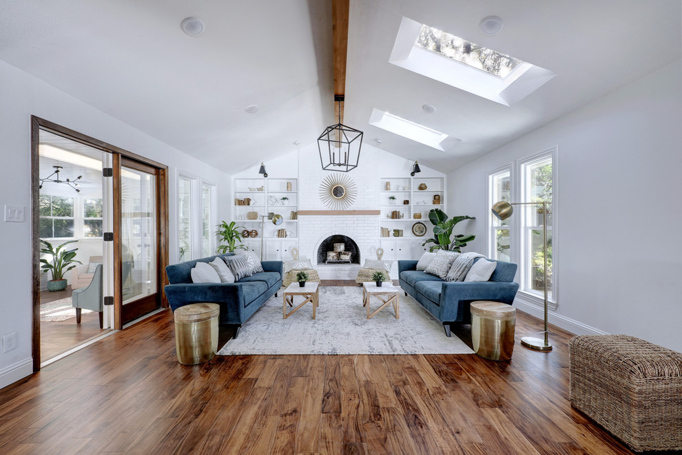 This is an example of a country formal enclosed living room in Austin with white walls, medium hardwood floors, a standard fireplace, a brick fireplace surround and brown floor.