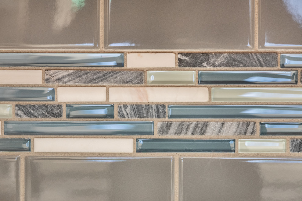Mid-sized transitional u-shaped vinyl floor and brown floor enclosed kitchen photo with an undermount sink, shaker cabinets, gray cabinets, quartz countertops, gray backsplash, subway tile backsplash, stainless steel appliances, no island and white countertops