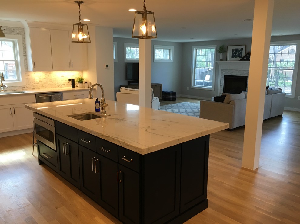 Mid-sized transitional u-shaped brown floor open concept kitchen photo in DC Metro with an undermount sink, shaker cabinets, white cabinets, gray backsplash, stainless steel appliances, an island and white countertops