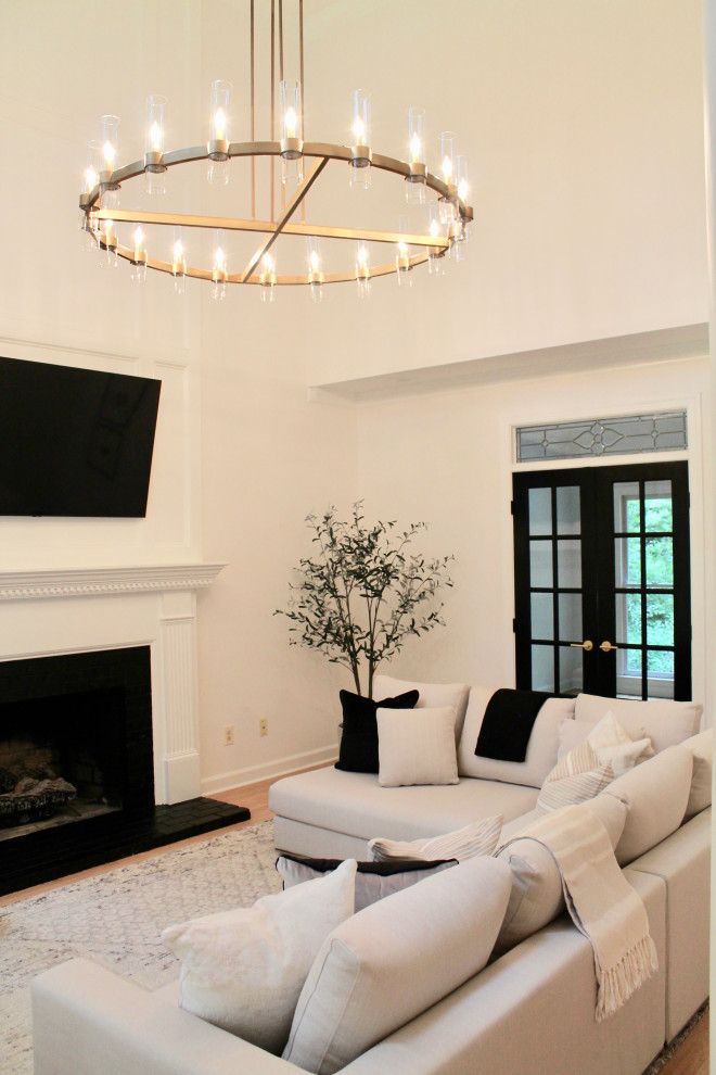 Inspiration for a medium sized modern enclosed games room in Raleigh with white walls, light hardwood flooring, a standard fireplace, a brick fireplace surround, a vaulted ceiling and wainscoting.