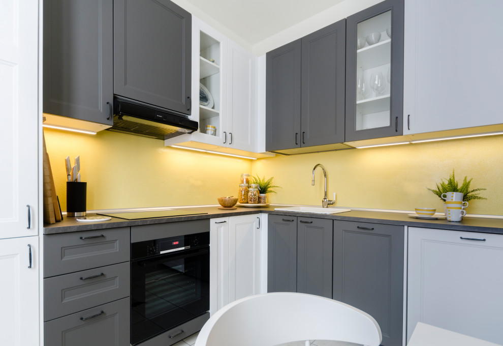 Photo of a small contemporary l-shaped eat-in kitchen in Milan with laminate benchtops, yellow splashback, panelled appliances, porcelain floors, no island, beige floor, grey benchtop, a single-bowl sink, recessed-panel cabinets and grey cabinets.