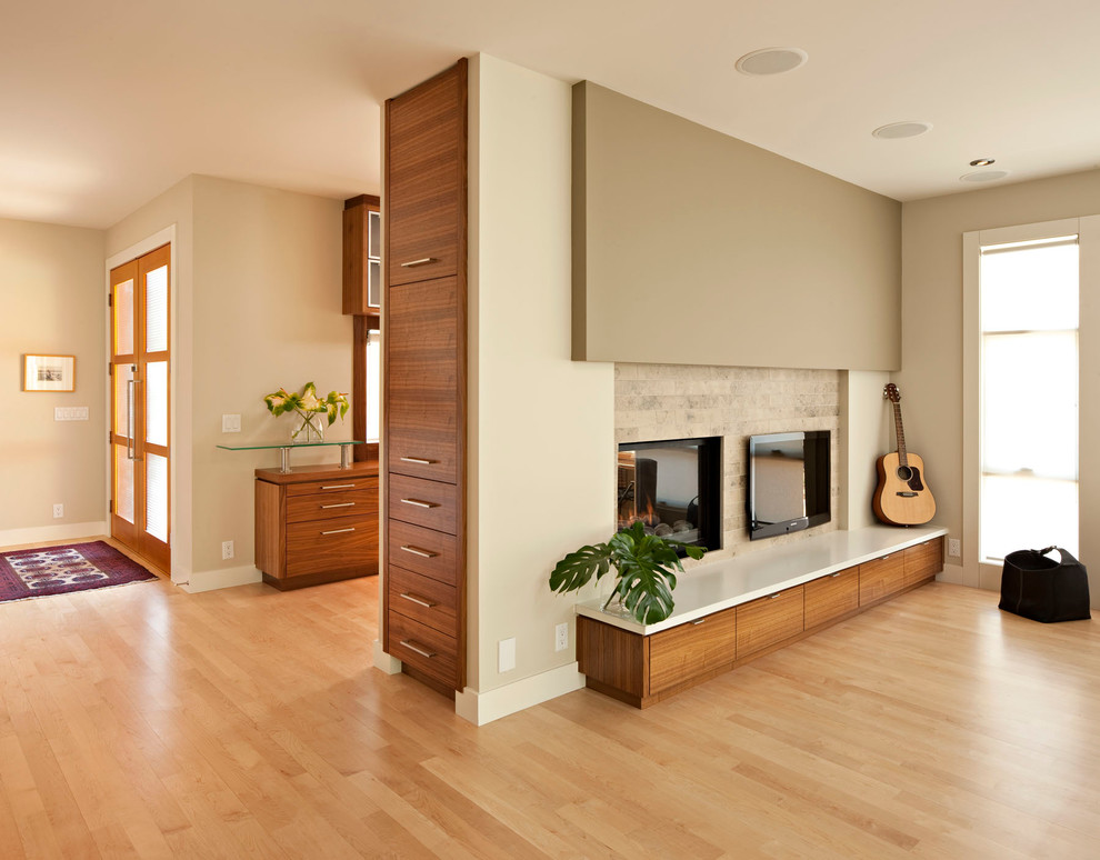 Design ideas for a modern living room in Calgary with beige walls, light hardwood floors and a two-sided fireplace.