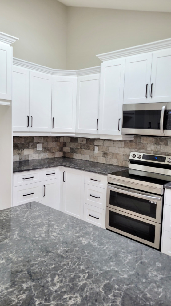 Inspiration for a transitional u-shaped open concept kitchen remodel with an undermount sink, recessed-panel cabinets, white cabinets, multicolored backsplash, stone tile backsplash, stainless steel appliances and a peninsula