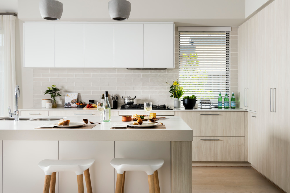This is an example of a contemporary kitchen in Perth with a double-bowl sink, flat-panel cabinets, light wood cabinets, beige splashback, subway tile splashback and light hardwood floors.
