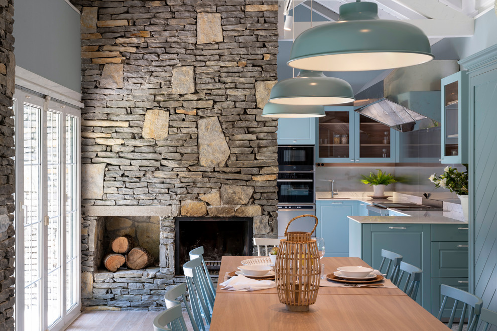 Modelo de comedor de cocina tradicional renovado extra grande con paredes azules, suelo laminado, todas las chimeneas, marco de chimenea de piedra y suelo marrón