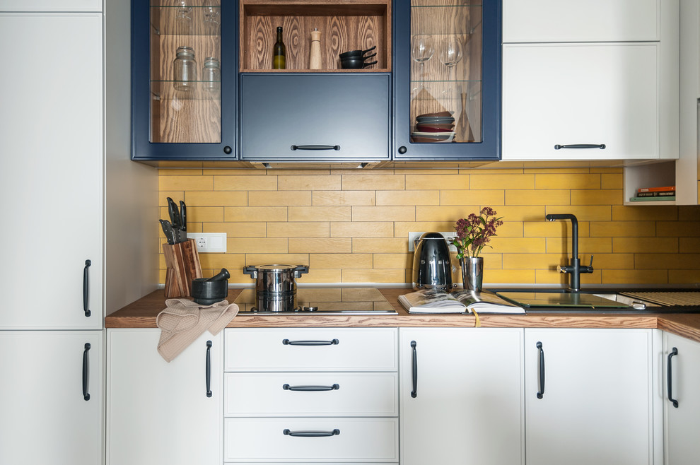 Inspiration for an eclectic l-shaped open plan kitchen in Other with a drop-in sink, beaded inset cabinets, white cabinets, wood benchtops, yellow splashback, no island, brown benchtop and porcelain splashback.