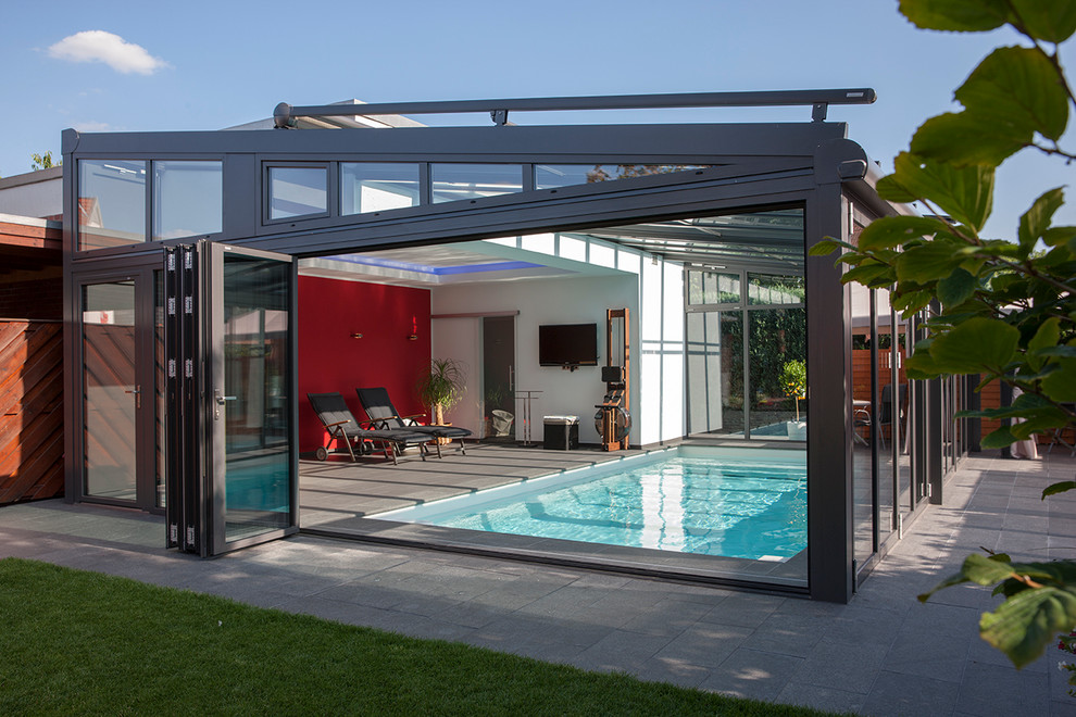 This is an example of a mid-sized contemporary indoor rectangular pool in Dortmund with concrete pavers.