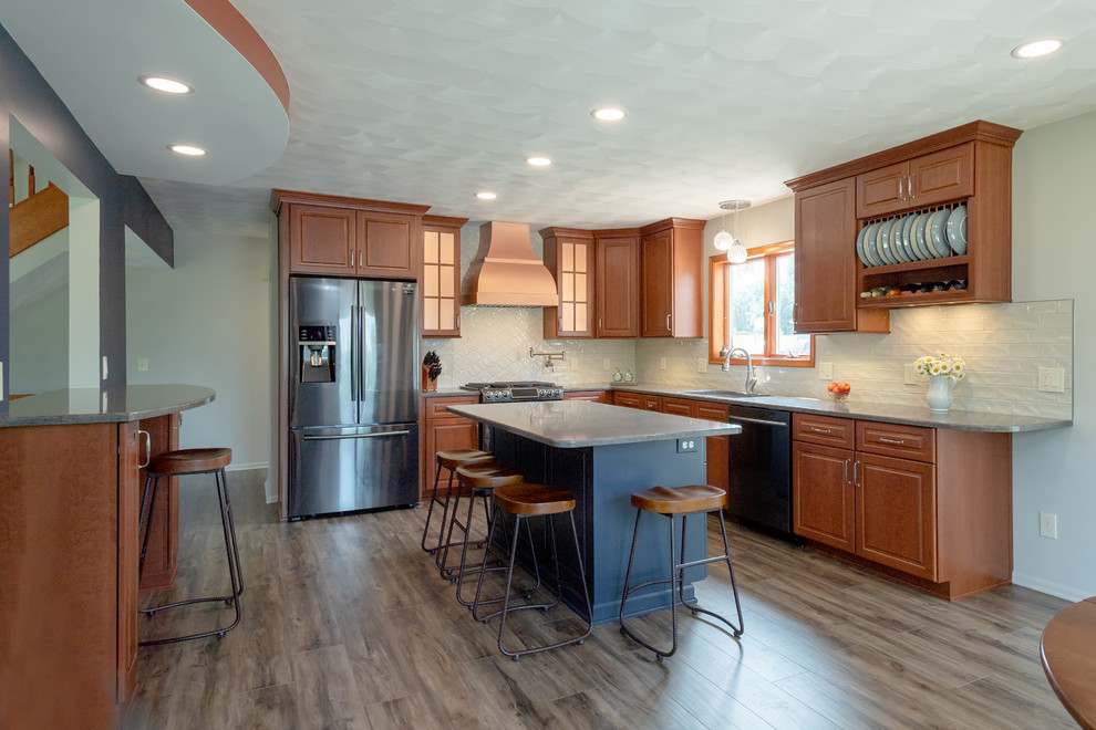 Example of a mid-sized transitional l-shaped vinyl floor and gray floor eat-in kitchen design with a double-bowl sink, raised-panel cabinets, medium tone wood cabinets, quartzite countertops, white backsplash, subway tile backsplash, stainless steel appliances, an island and gray countertops