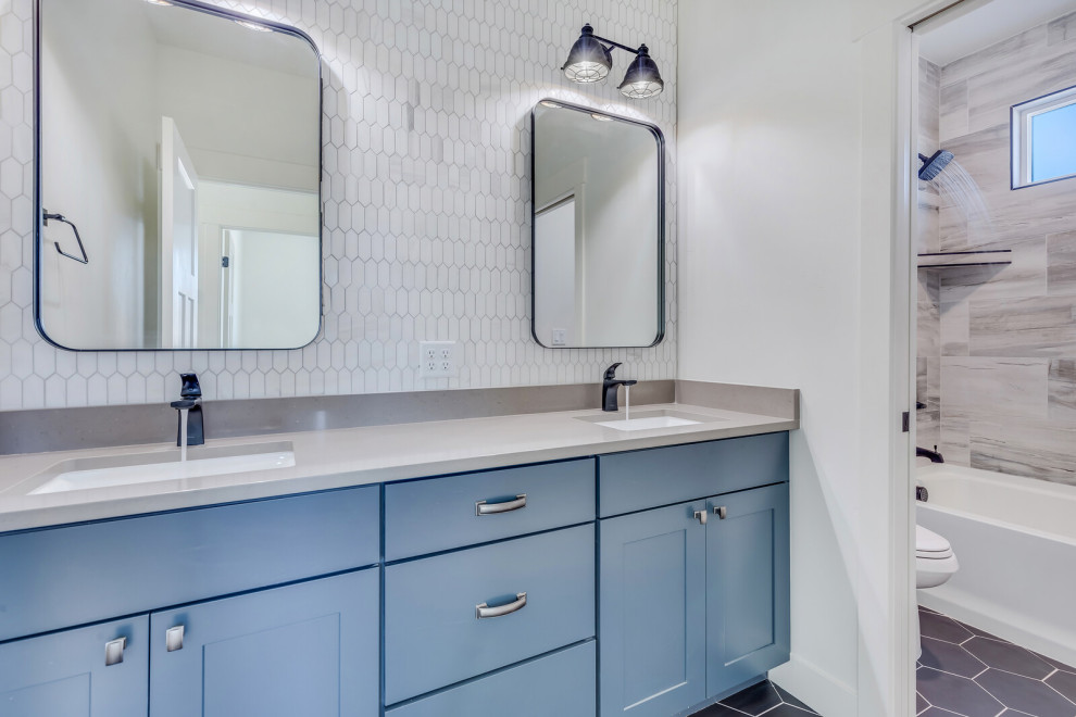 На фото: детская ванная комната среднего размера в современном стиле с фасадами с выступающей филенкой, синими фасадами, ванной в нише, душем над ванной, раздельным унитазом, белой плиткой, керамической плиткой, белыми стенами, полом из керамической плитки, врезной раковиной, столешницей из искусственного кварца, черным полом, шторкой для ванной, серой столешницей, тумбой под две раковины, встроенной тумбой и нишей