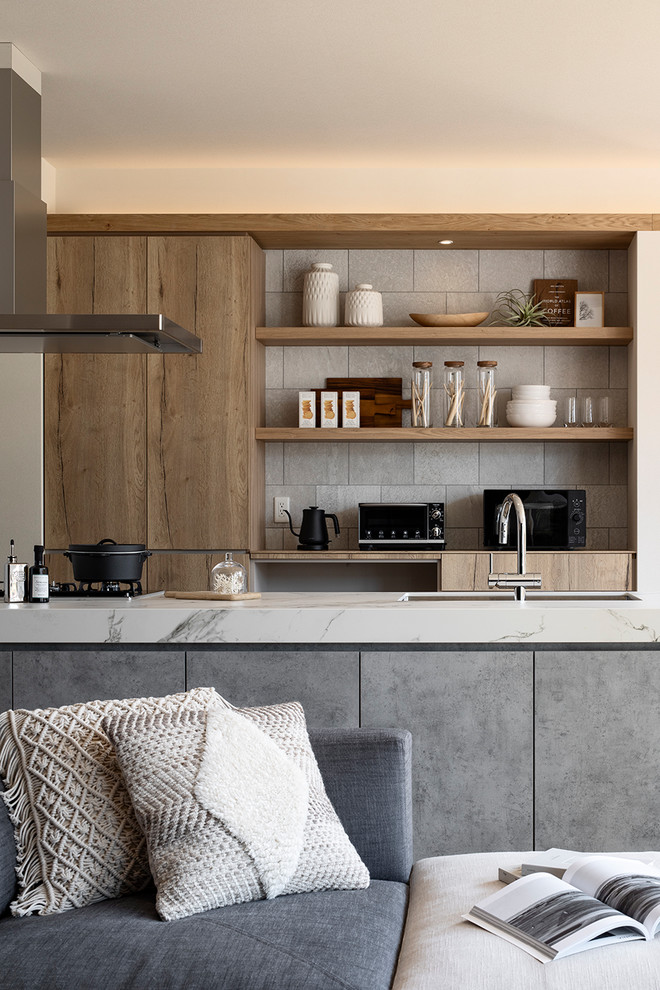 Photo of a contemporary galley open plan kitchen in Tokyo with an undermount sink, quartz benchtops, a peninsula, white benchtop, flat-panel cabinets, medium wood cabinets and grey splashback.