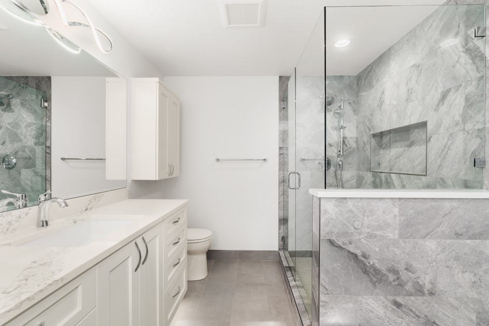 Inspiration for a medium sized contemporary bathroom in Seattle with shaker cabinets, white cabinets, a freestanding bath, grey tiles, porcelain tiles, white walls, porcelain flooring, a submerged sink, engineered stone worktops, grey floors, a hinged door, white worktops, a wall niche, a single sink and a built in vanity unit.