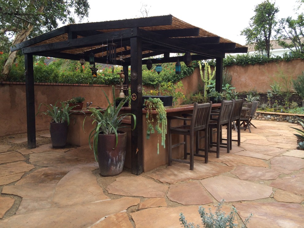 Inspiration for a mid-sized mediterranean backyard patio in Los Angeles with an outdoor kitchen, natural stone pavers and a pergola.