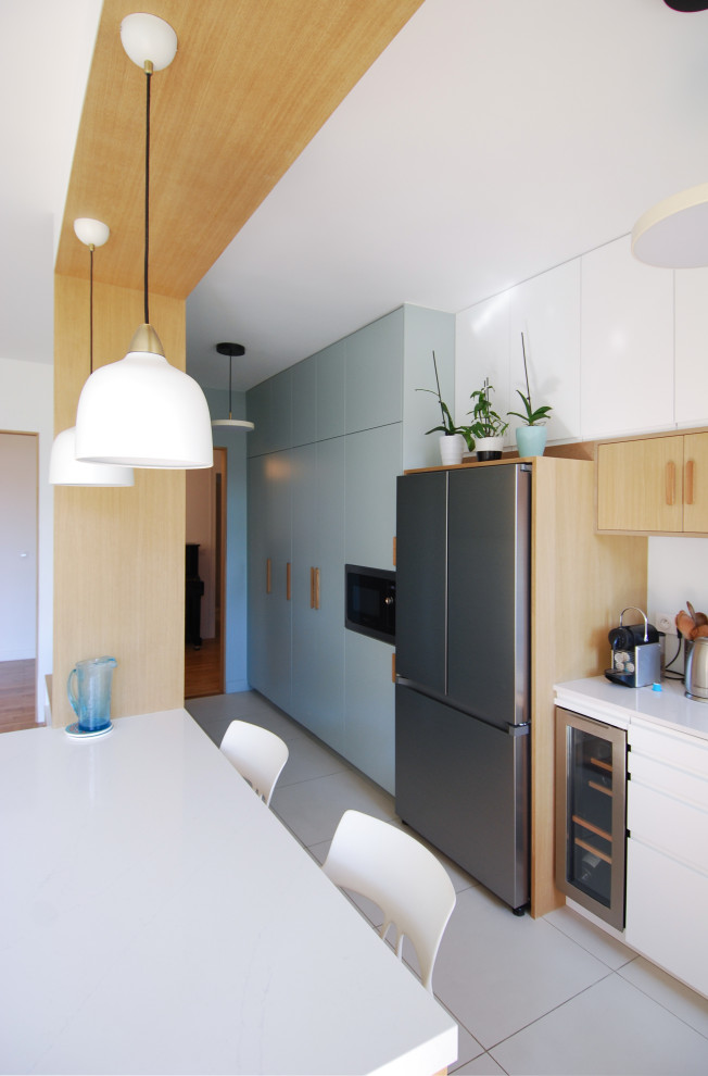 Inspiration for a large contemporary single-wall open plan kitchen in Paris with an integrated sink, beaded inset cabinets, blue cabinets, quartz benchtops, white splashback, glass sheet splashback, stainless steel appliances, ceramic floors, with island, beige floor and white benchtop.