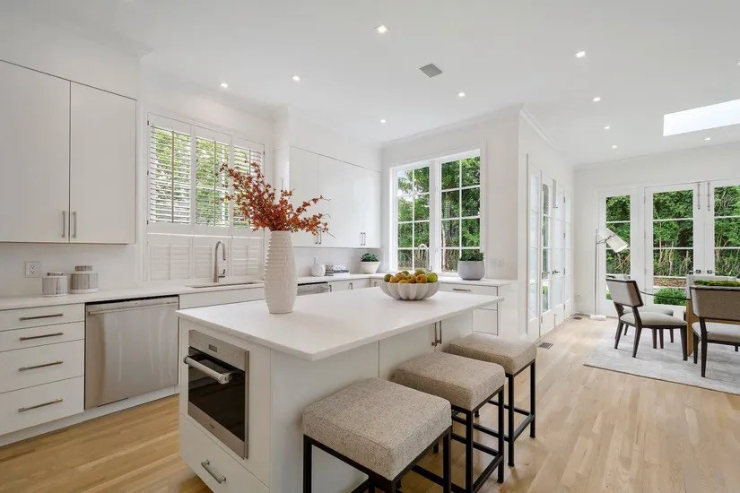 Inspiration for a large traditional u-shaped eat-in kitchen in New York with a farmhouse sink, flat-panel cabinets, white cabinets, quartz benchtops, white splashback, brick splashback, stainless steel appliances, bamboo floors, with island, beige floor, white benchtop and wood.