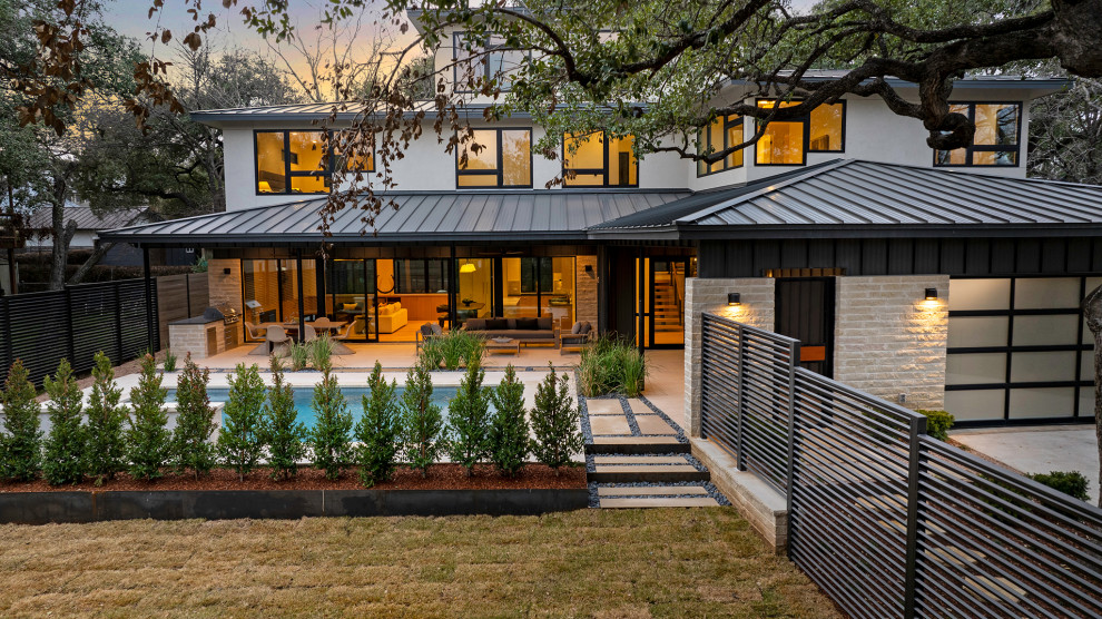 Diseño de fachada de casa beige y marrón moderna grande de tres plantas con revestimiento de piedra y tejado de metal