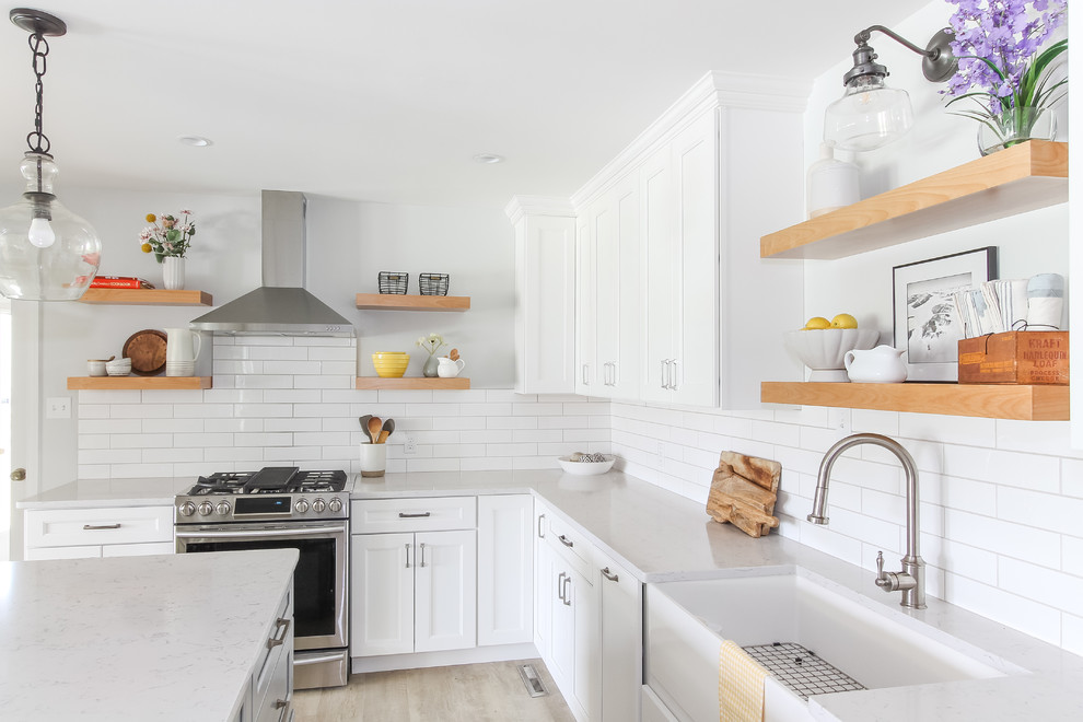 Inspiration for a large country u-shaped separate kitchen in DC Metro with a farmhouse sink, recessed-panel cabinets, white cabinets, quartz benchtops, white splashback, subway tile splashback, stainless steel appliances, vinyl floors, with island and white benchtop.