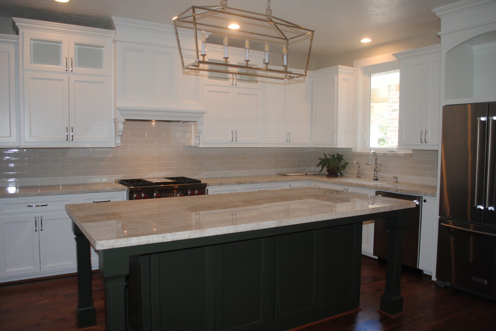 Inspiration for a mid-sized transitional l-shaped dark wood floor and brown floor open concept kitchen remodel in Houston with a farmhouse sink, raised-panel cabinets, white cabinets, quartzite countertops, beige backsplash, ceramic backsplash, stainless steel appliances, an island and white countertops