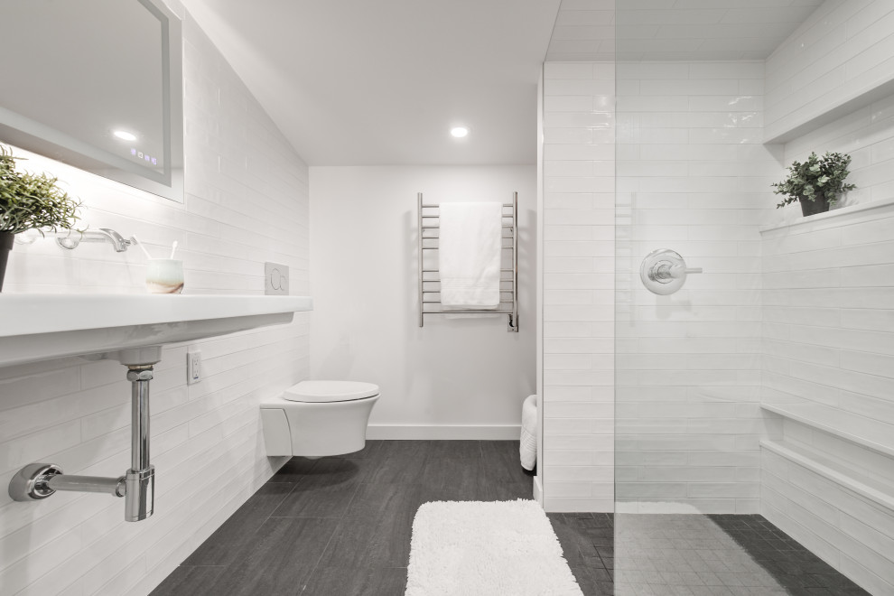 Idéer för små 60 tals en-suite badrum, med en kantlös dusch, en vägghängd toalettstol, vit kakel, keramikplattor, vita väggar, ett väggmonterat handfat, grått golv och med dusch som är öppen